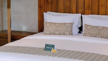 A hotel room with a wooden headboard, a bed with white bedding, and a small table with a 'Thank You' sign.