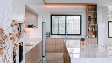 Una cocina moderna con un amplio ventanal, armarios de madera y encimera de mármol.