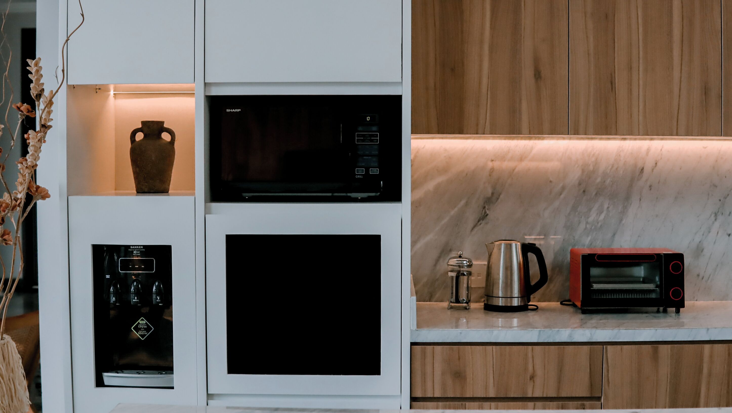 Una cocina con microondas, cafetera y tostadora sobre la encimera.