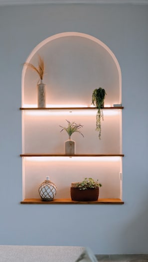 Een wandplank met drie planken, elk gevuld met diverse decoratieve objecten.