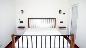Une chambre à coucher avec un lit, une tête de lit en bois, des tables de chevet et une porte.