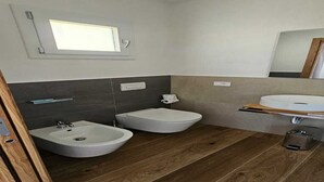 Un baño moderno con un bidé, un lavamanos y un espejo.