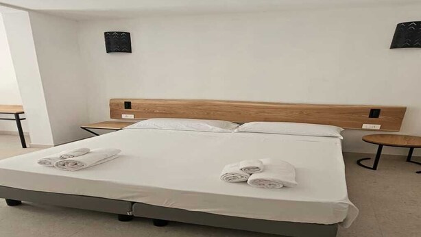 Una habitación de hotel moderna con una cama grande, dos mesitas de noche y una pequeña mesa redonda.