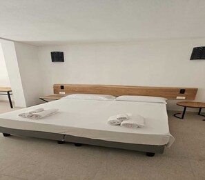A modern hotel room with a large bed, two bedside tables, and a small round table.