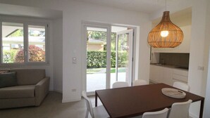 Une cuisine moderne avec des armoires blanches et un plan de travail foncé. On y trouve une table à manger avec quatre chaises, et un luminaire suspendu au-dessus.