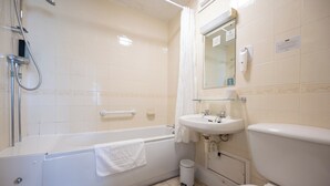 Une salle de bain équipée d’une baignoire, d’un lavabo, de toilettes, d’un miroir et d’un sèche-mains.