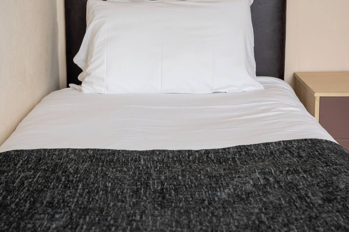 A neatly made bed with white linens and a dark headboard.
