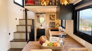 Een moderne keuken met een inbouw kookeiland, een eethoek met rieten stoelen, en uitzicht door een groot raam.