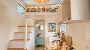 Een moderne keuken met een centraal eiland, een hanglamp en uitzicht op het platteland door het raam.