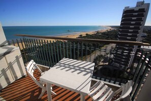 A balcony with a view of the beach and ocean, white furniture, and a metal railing. - Holiday apartment with air conditioning and balcony with sea view (Lignano Sabbiadoro)
