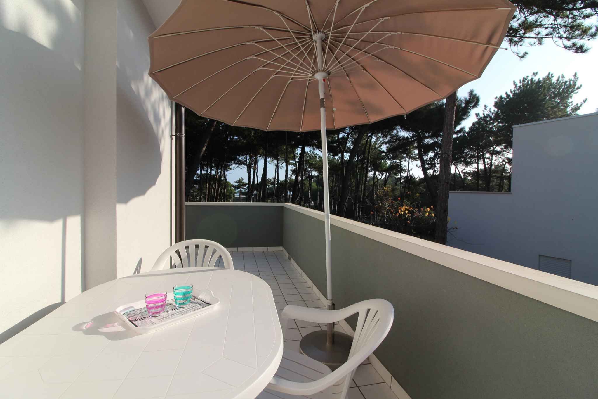 Een balkon met een tafel, stoelen en een parasol.