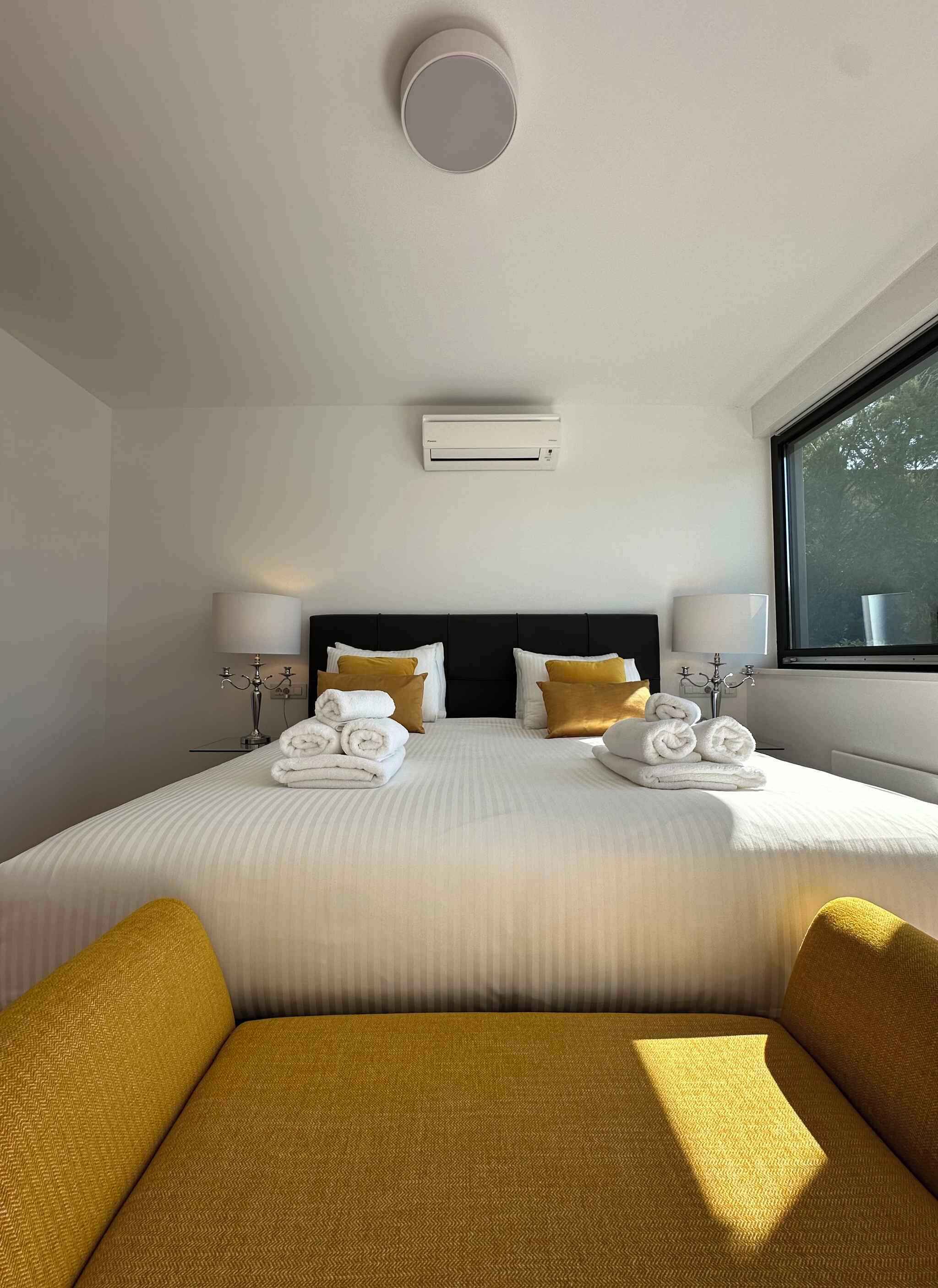 Una camera d'albergo con un letto grande, due lampade ai comodini, una finestra e una luce a soffitto.