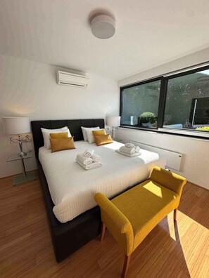 Ein modernes Hotelzimmer mit einem großen Bett, Nachttischlampen, einem Fenster mit Blick und einem kleinen Tisch.