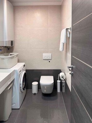 Ein kleines Badezimmer mit Waschmaschine, Toilette und Handtuchhalter.