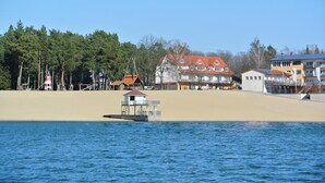 A coastal area with a lighthouse, beach houses, and a small boat on the water. - Bernsteinsee Hotel and Ferien Lakeview Balcony (Sassenburg)