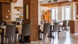 A restaurant with brick walls, wooden beams, and wicker chairs. - Bernsteinsee Hotel and Ferien Lakeview Balcony (Sassenburg)