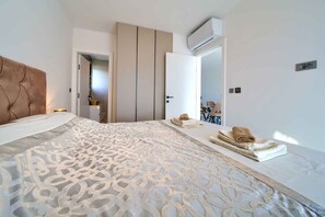 Ett hotellrum med en stor säng, en garderob, en luftkonditioneringsanläggning och ett badrum som syns genom en öppen dörr.