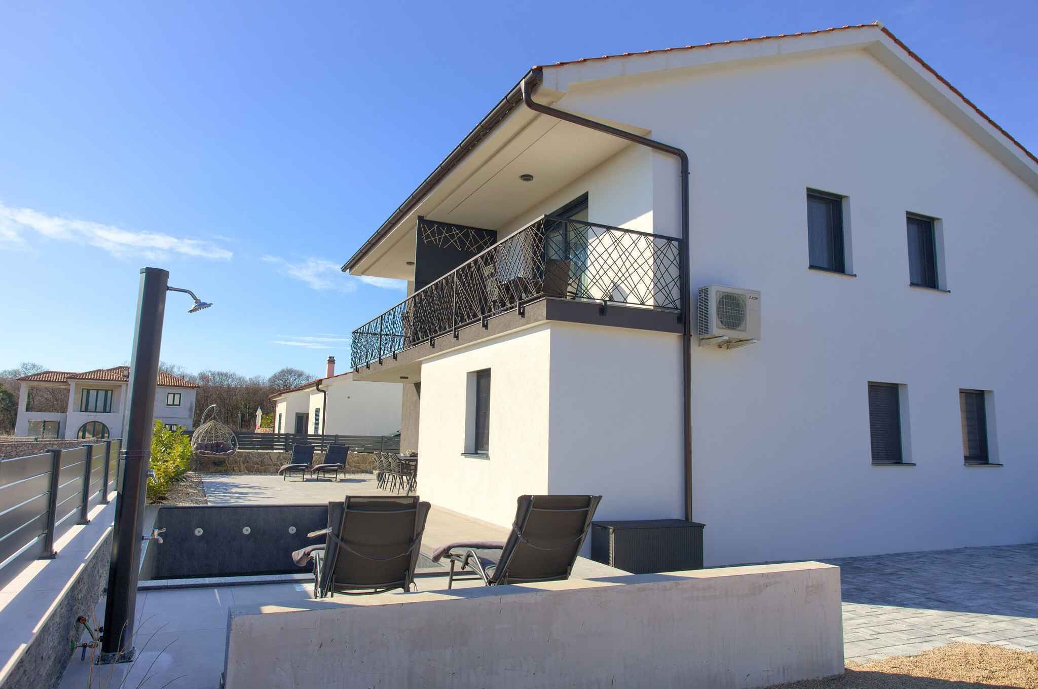 A modern building with a balcony, outdoor seating, and an air conditioning unit.