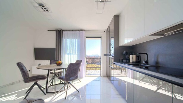 Eine moderne Küche mit Essbereich, großem Fenster und Blick ins Freie.