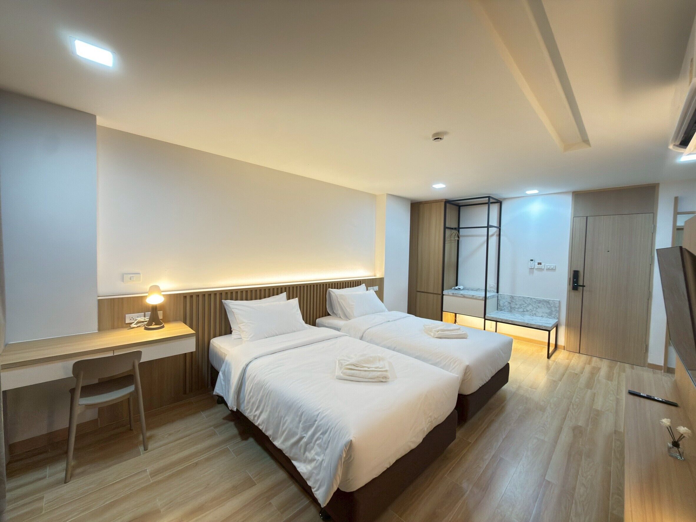 Habitación de hotel con dos camas, un escritorio, una silla, un armario y un baño con ducha.