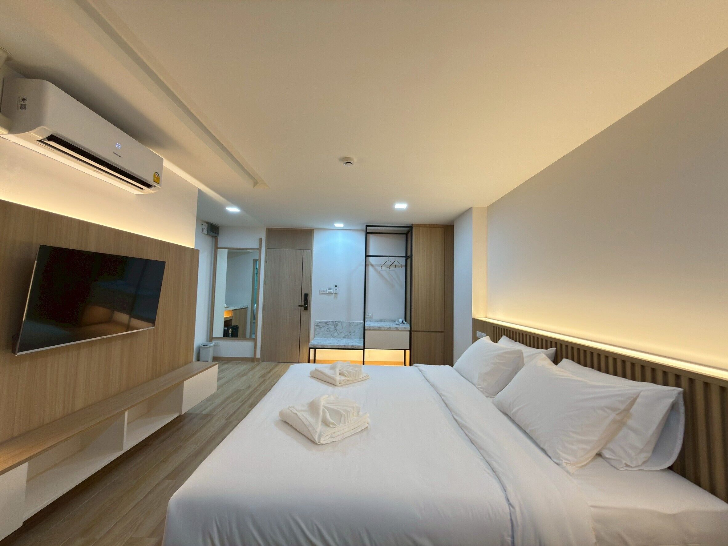 Une chambre d’hôtel moderne dotée d’un grand lit, d’une télévision à écran plat, d’une armoire intégrée et d’un miroir.