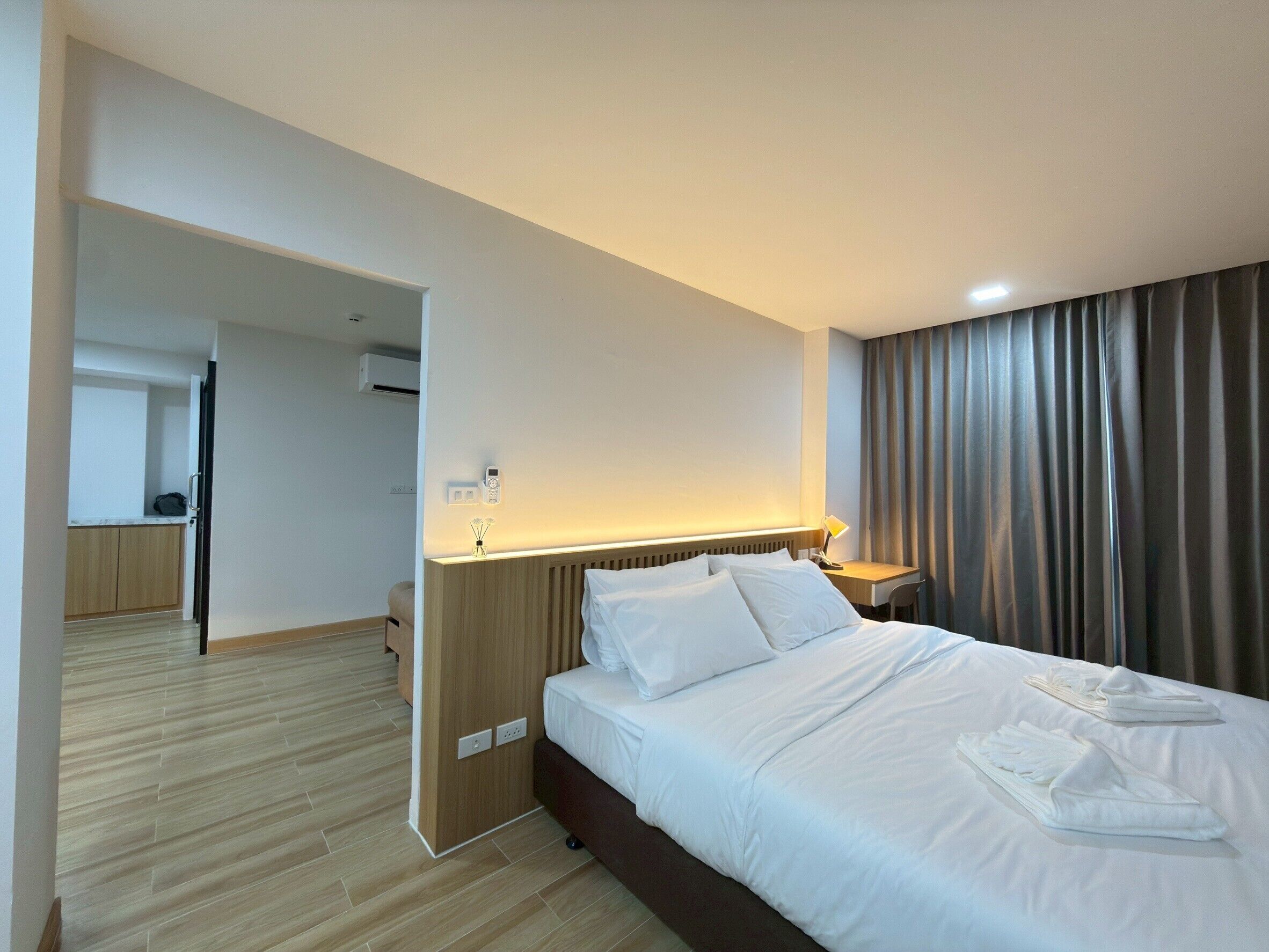 A hotel room with a bed, a desk, a chair, and a bathroom visible through an open door.