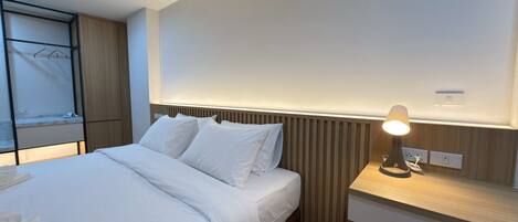 A modern hotel room with a neatly made bed, a bedside table with a lamp, and a built-in wardrobe.