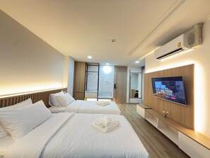 Een hotelkamer met twee bedden, een televisie en een houten garderobe.