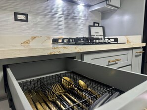 A kitchen with a marble countertop, a gas stove, and a drawer with utensils.