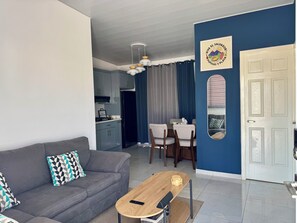 Uma sala de estar moderna com um sofá cinzento, uma mesa de centro de madeira e um espaço de jantar com mesa e cadeiras.
