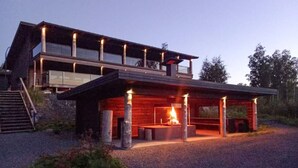A modern two-story building with a covered outdoor seating area and a fire feature.