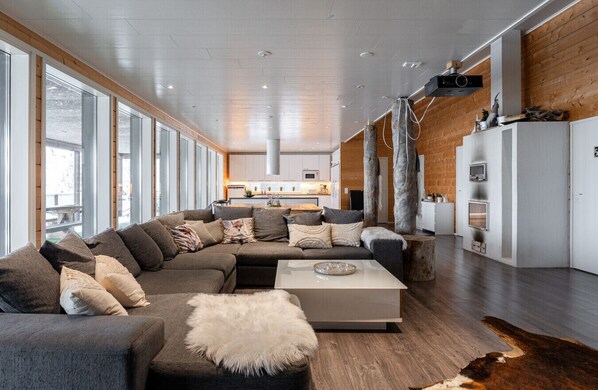 A modern living room with a large sectional sofa, a coffee table, and a fireplace.