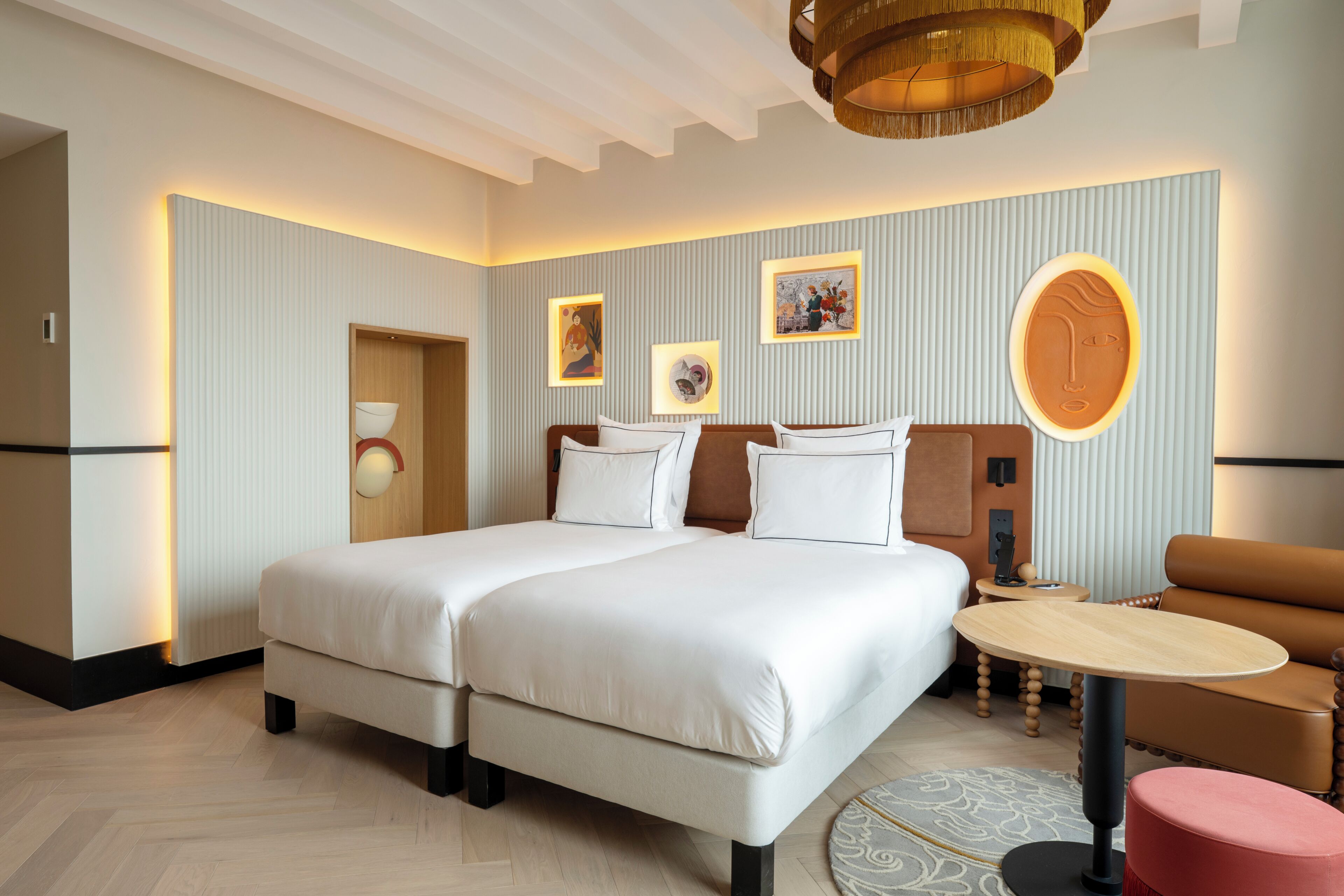 Habitación de hotel con una cama grande, una mesa redonda, un sofá y una obra de arte colgada en la pared.