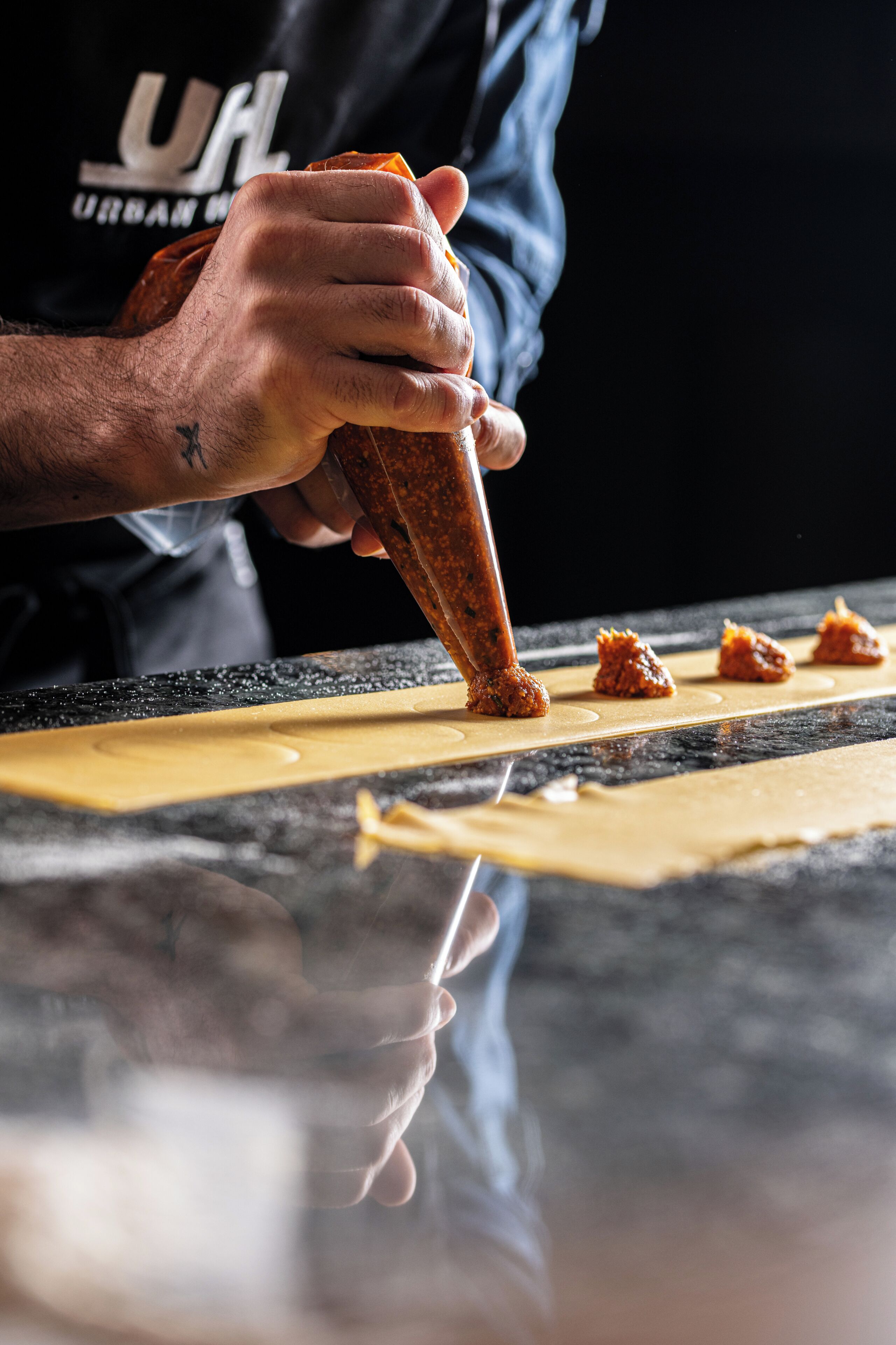 Una persona omplint figures de pastissos en una safata de forn amb una bossa de pastisseria.