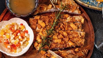 Una mesa de madera con un plato de comida, un tazón de sopa y un recipiente pequeño de verduras picadas.