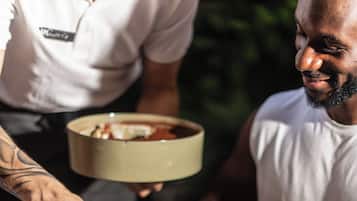 Una persona sirve un postre en un plato con una rodaja de naranja al lado.