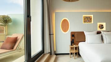 Una habitación de hotel con un ventanal grande, una cama, una mesita y una obra de arte colgada en la pared.
