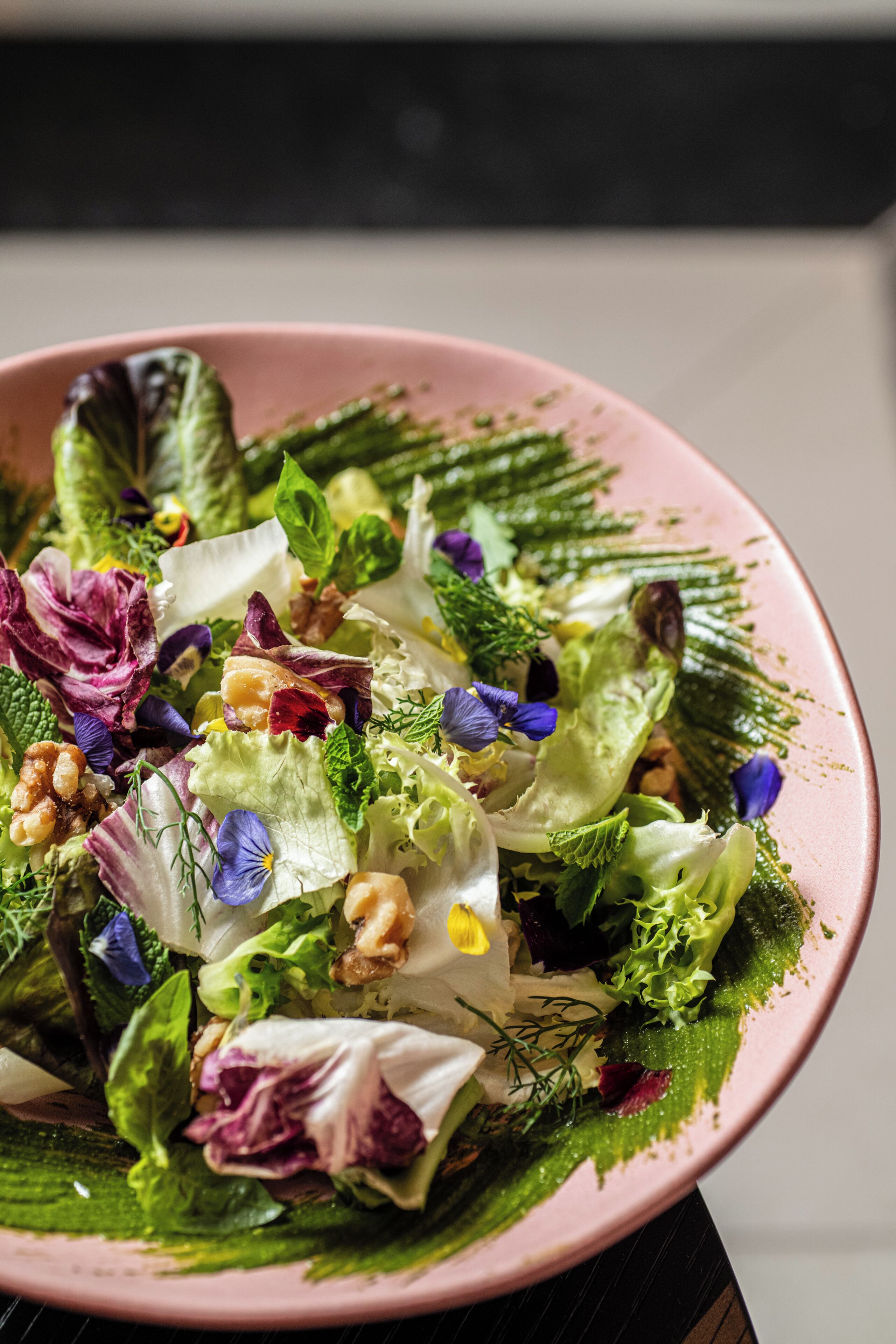 A bowl of salad with various greens and flowers.