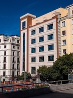 A multi-story building with a modern architectural style, featuring a central vertical element and multiple windows.