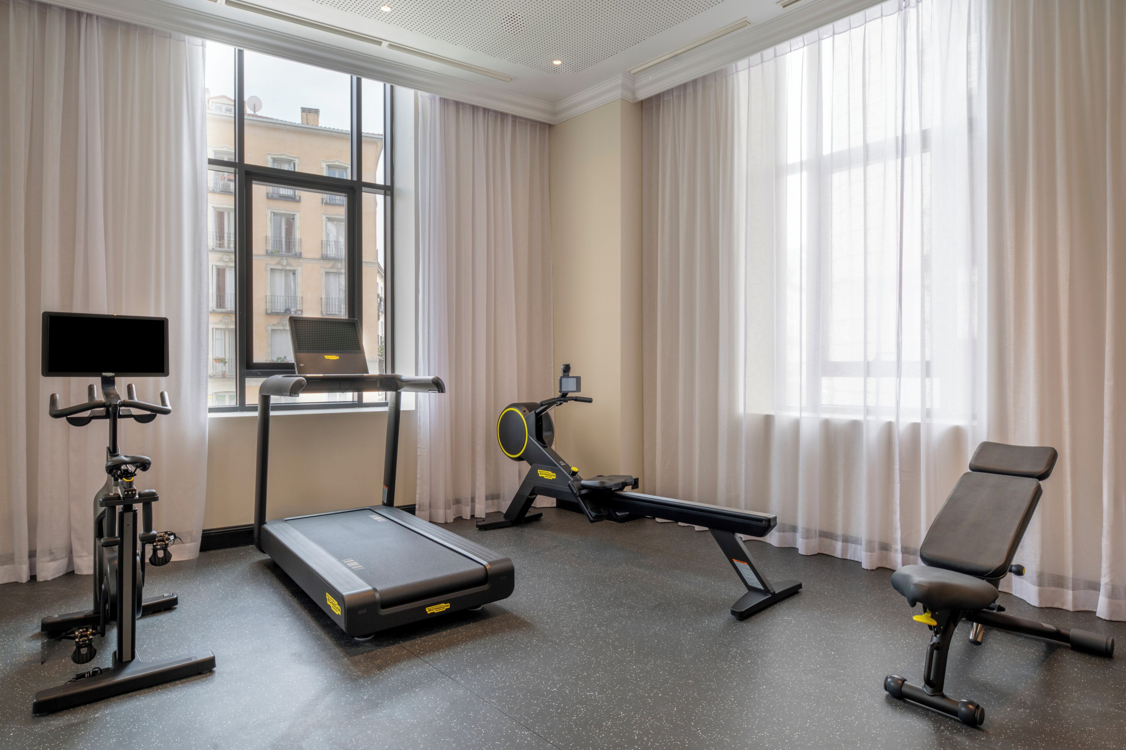 Une salle de sport équipée d’un tapis de course, d’un vélo d’exercice et d’un rameur.