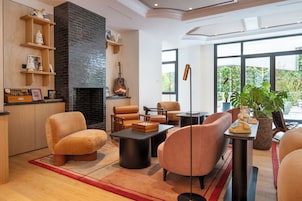 A modern living room with a fireplace, comfortable seating, and large windows.