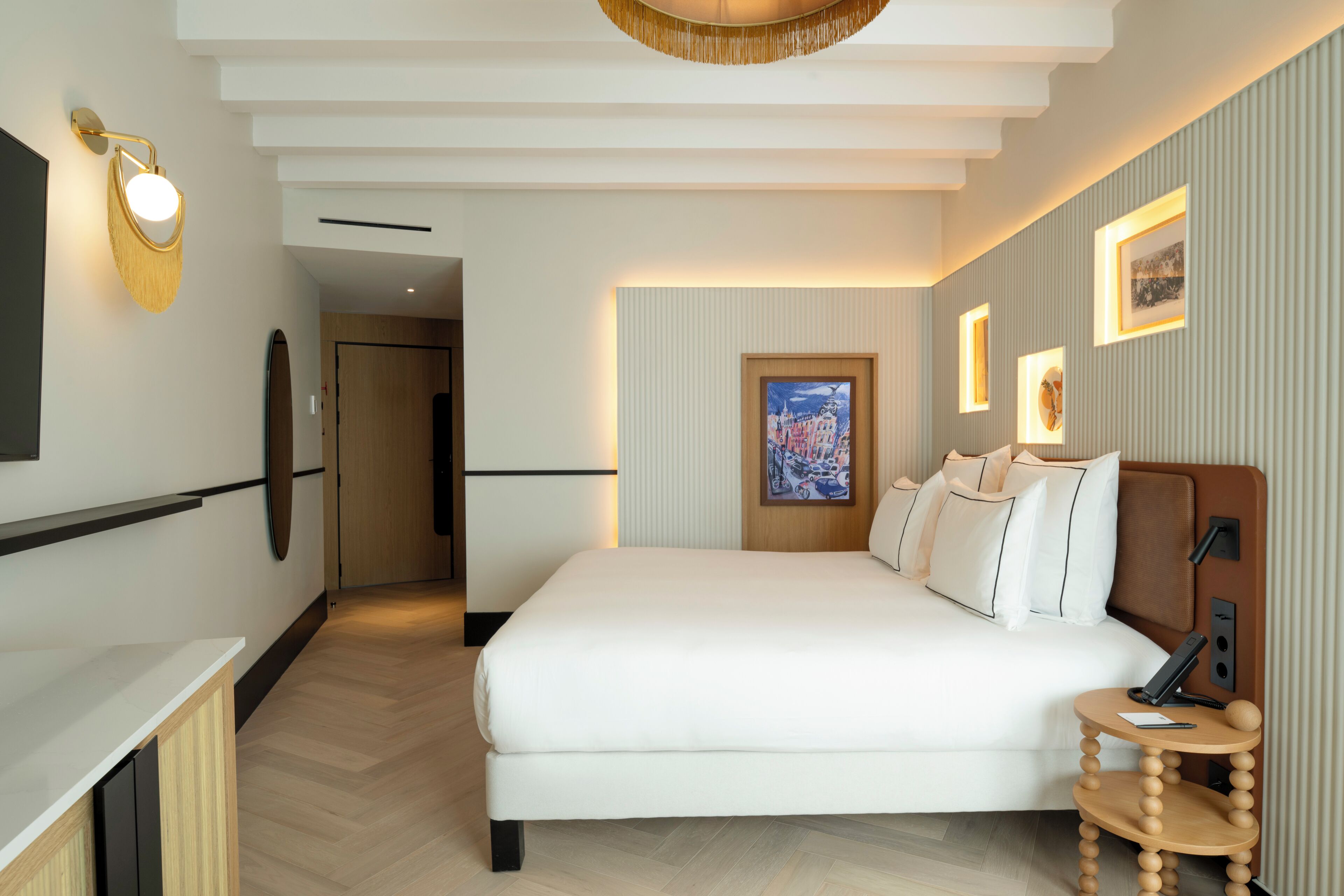 Habitación de hotel con una cama grande, una mesita de noche, una lámpara de pared y un cuadro enmarcado en la pared.