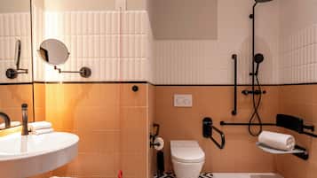 A bathroom with a sink, mirror, toilet, and shower.