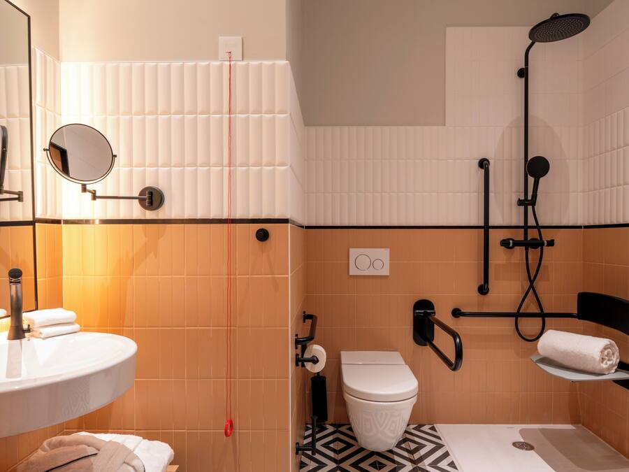 A bathroom with a sink, mirror, toilet, and shower.