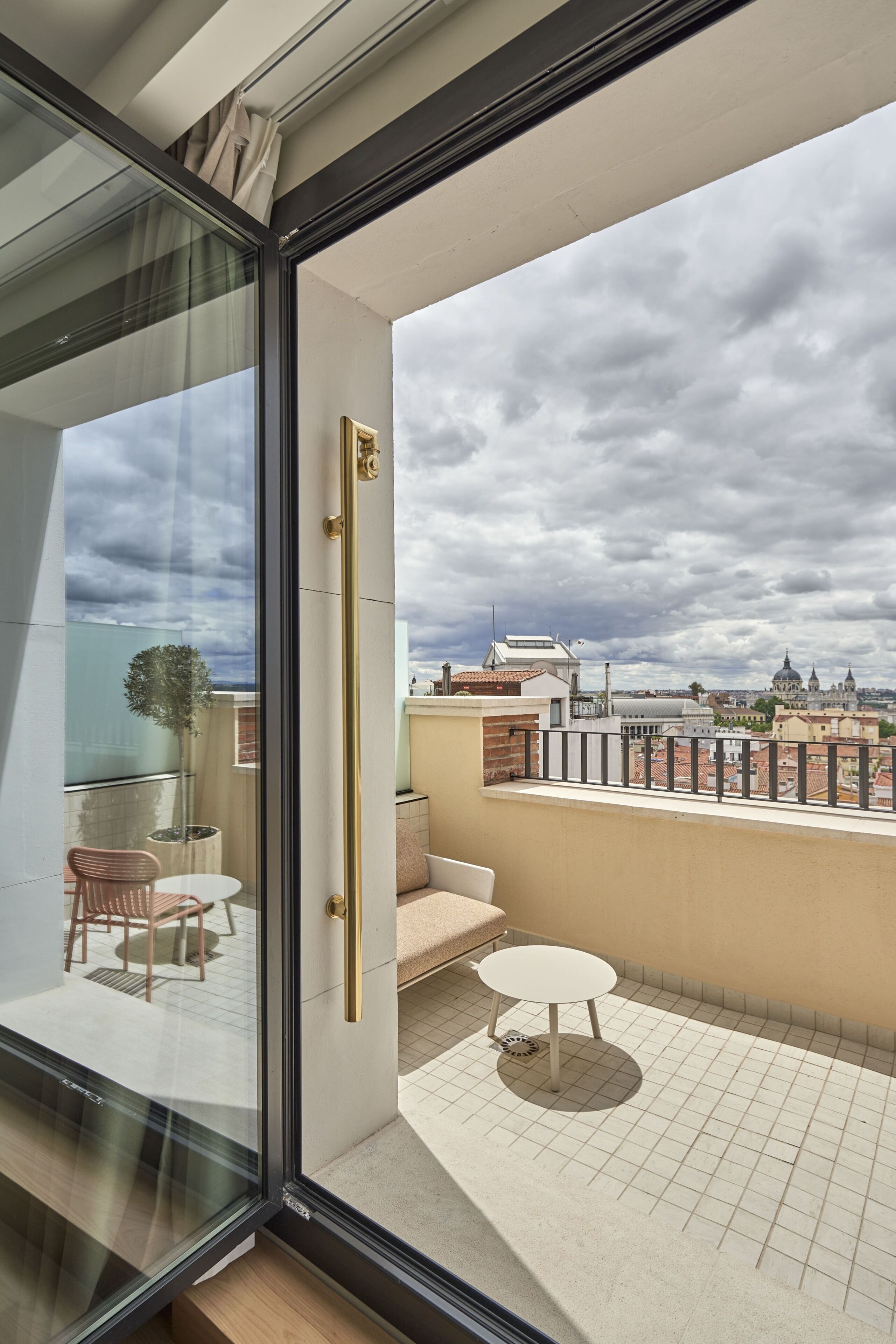 A balcony with a glass door, a round table, and a chair.