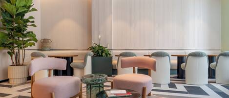 A modern lobby with seating, a coffee table, and a large plant.