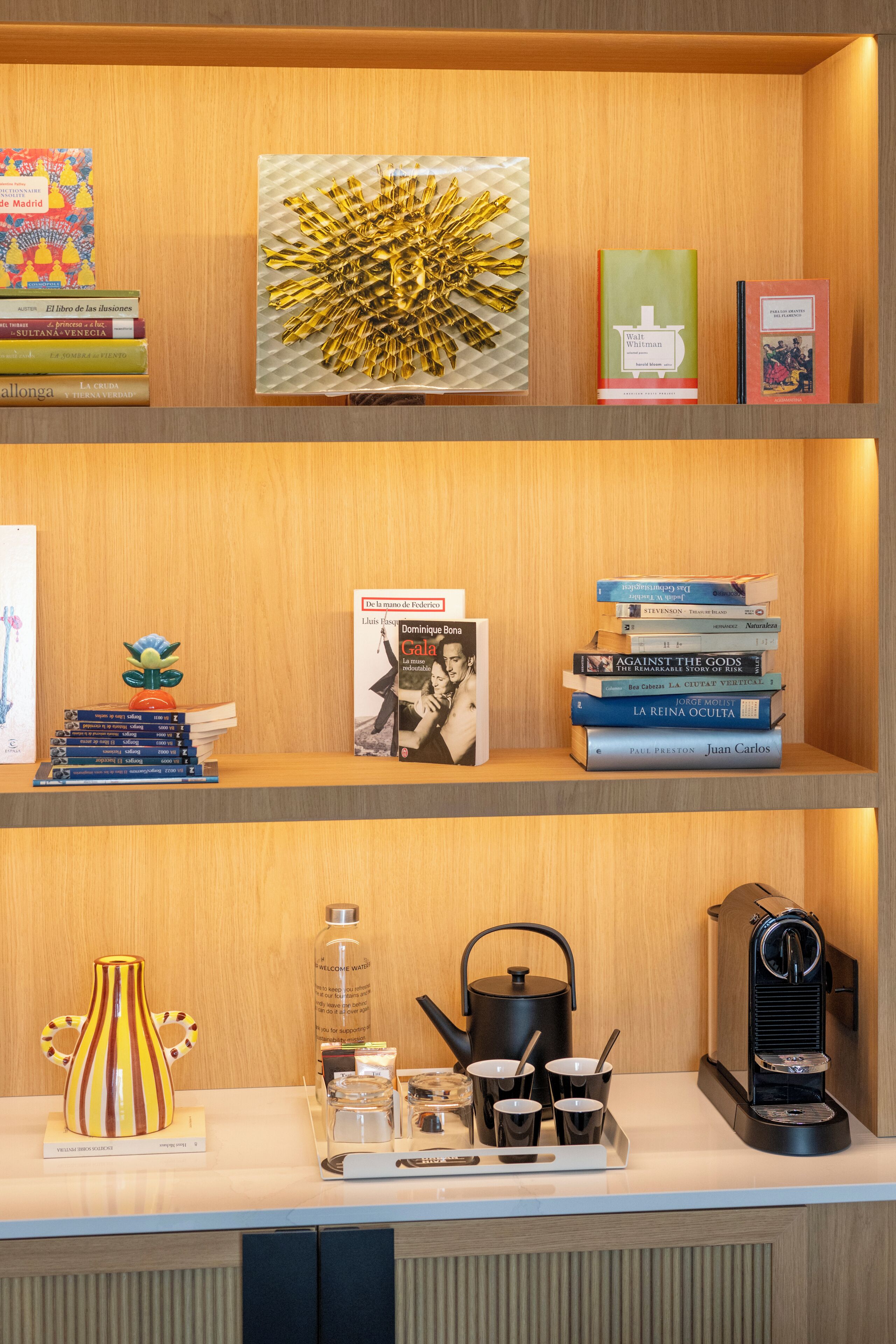 A wooden shelf with books, a decorative item, and a coffee machine.