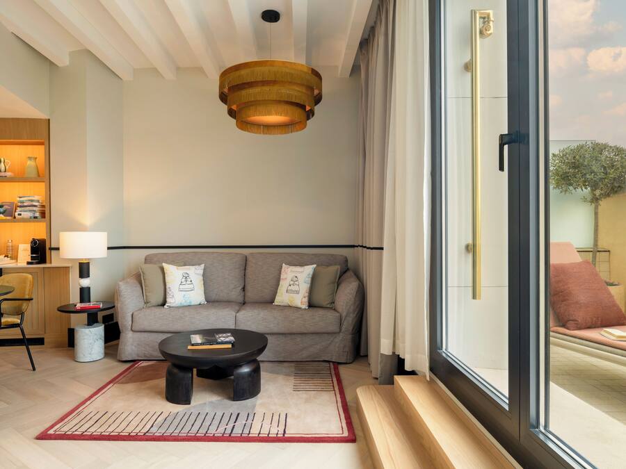 Una sala de estar moderna con sofá, mesa de centro y una lámpara colgante.