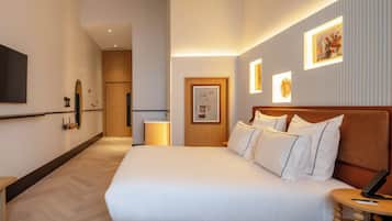 Una camera d'albergo con un letto grande, comodini, una TV a schermo piatto e opere d'arte incorniciate alle pareti.