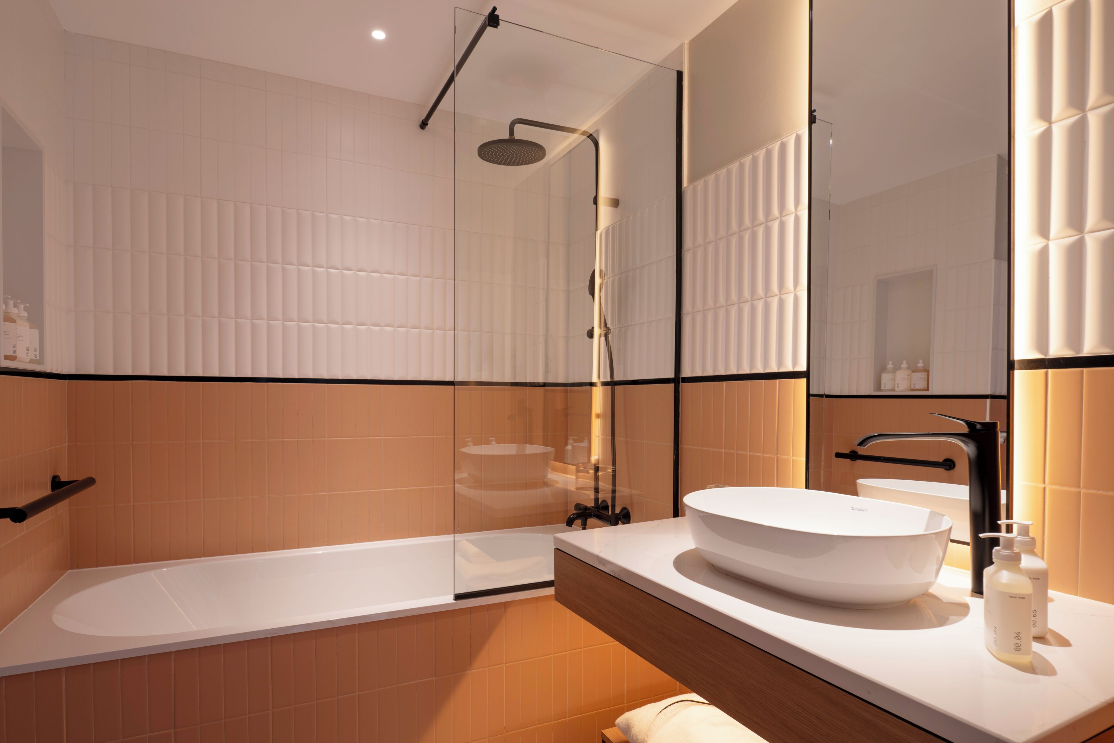 Une salle de bain moderne dotée d’une grande baignoire, d’une douche à parois de verre et d’un meuble-lavabo avec un grand évier.